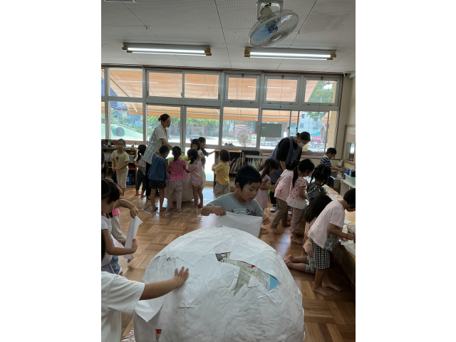 下地が見えなくなるようにペタペタ。「こっちにも貼って！」気づいて声を掛ける子もいます。