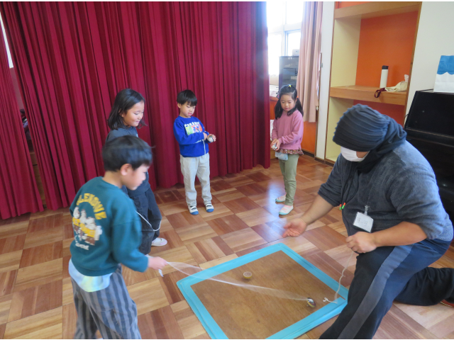 真剣に先生がこまを回すのを見ています