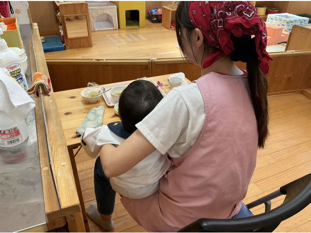 一人で自分の身体を支えられるようになるまで保育士の膝の上に座って食べます。