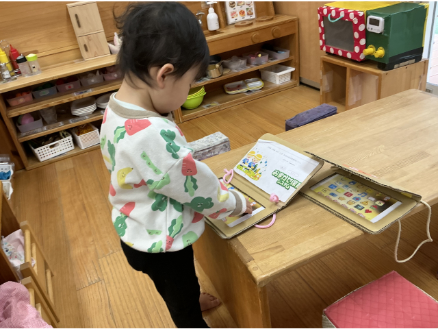 保育士の真似をして、手作りのPCで仕事中