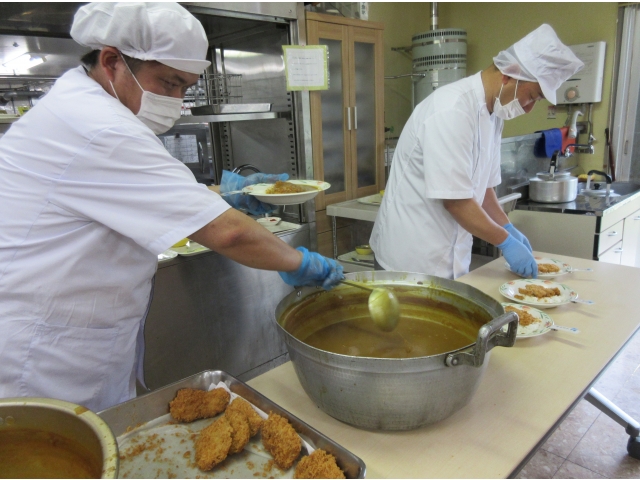 調理師さんがカレーの盛り付けをしています。