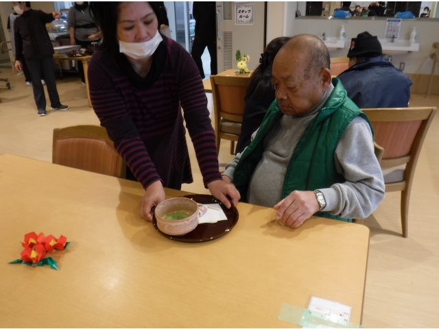 利用者様がお抹茶と和菓子をお持ちします