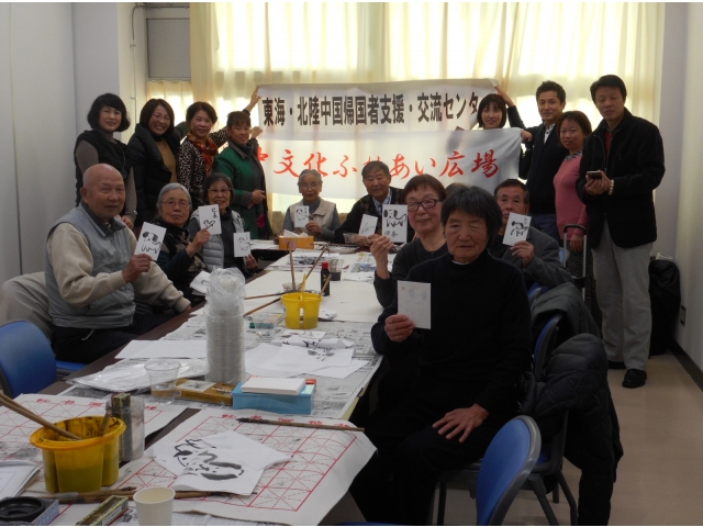 ハガキ大の紙に描いた作品を手に、記念写真。